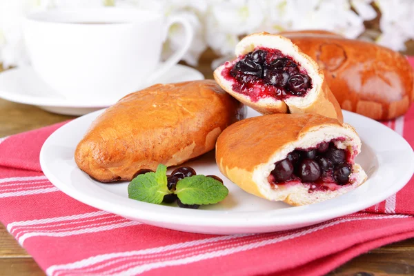 Fresh baked pasties with currant on plate on table close-up — Stock Photo, Image