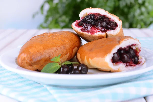 Fresh baked pasties with currant on plate on table close-up — Stock Photo, Image