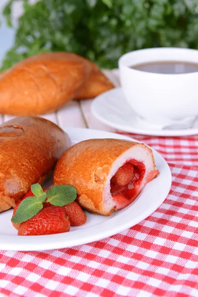 Fresh baked pasties with strawberries on plate on table close-up — Stock Photo, Image