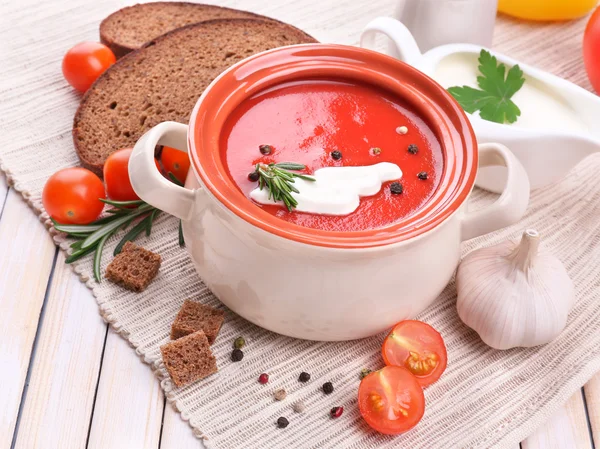 Tasty tomato soup and vegetables on wooden table — Stock fotografie