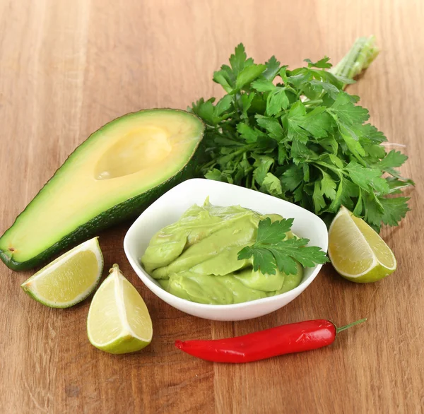 Guacamole fresco na tigela na mesa de madeira — Fotografia de Stock