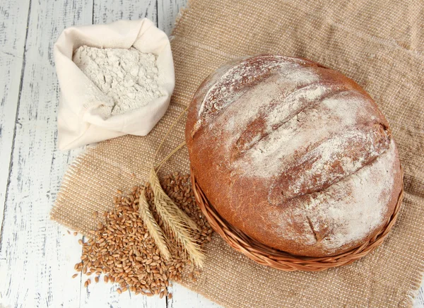 Pan de centeno con harina y granos sobre tela de saco sobre fondo de madera —  Fotos de Stock