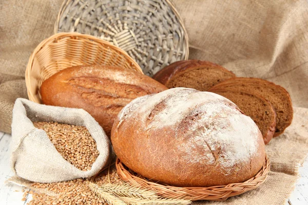 Pan de centeno con granos en la mesa sobre fondo de saco — Foto de Stock
