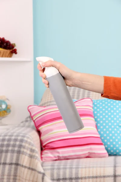 Sprayed air freshener in hand on home interior background — Stock Photo, Image