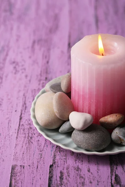 Composición con piedras de spa, vela sobre tabla de madera de color, sobre fondo claro —  Fotos de Stock