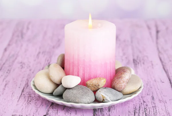 Композиция со спа-камнями, свечи на цветном деревянном столе, на светлом фоне — стоковое фото