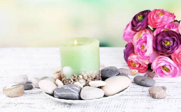 Composição com pedras de spa, vela e flores na mesa de madeira cor, no fundo claro — Fotografia de Stock