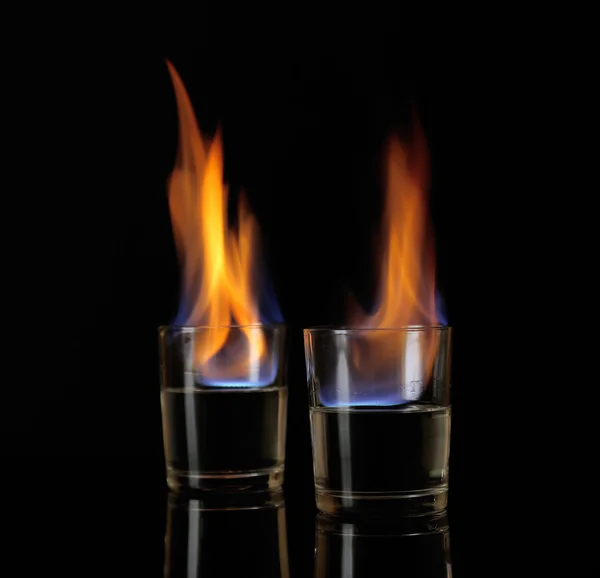 Glasses with burning alcohol on black background — Stock Photo, Image