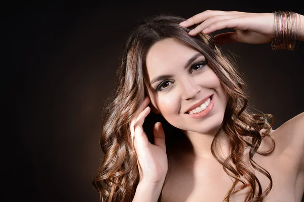 Hermosa joven con el pelo largo sobre fondo marrón oscuro —  Fotos de Stock