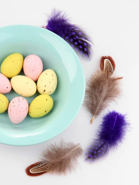 Huevos de Pascua en tazón y plumas decorativas aisladas en blanco —  Fotos de Stock