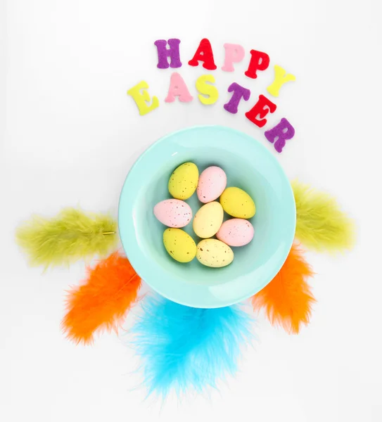 Easter eggs in bowl and decorative feathers isolated on white — Stock Photo, Image