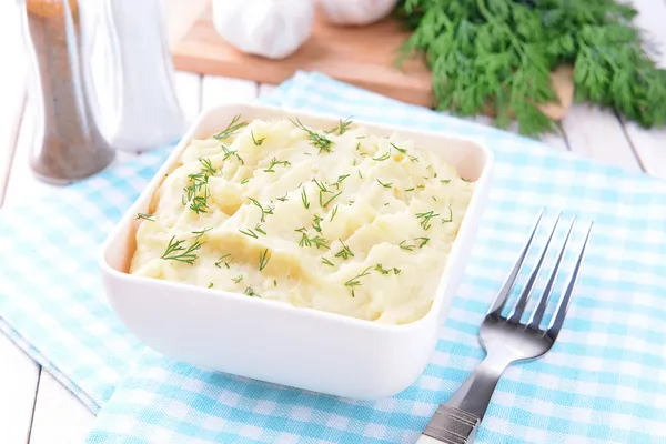 Вкусное картофельное пюре с зеленью в миске на столе крупным планом — стоковое фото
