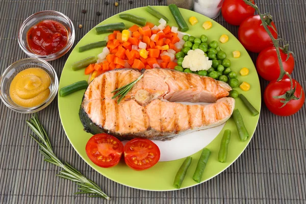 Tasty grilled salmon with vegetables, on bamboo mat — Stock Photo, Image