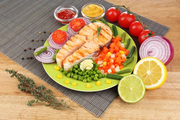 Sabroso salmón a la parrilla con verduras, sobre mesa de madera —  Fotos de Stock