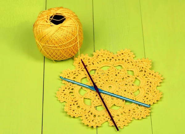 Yellow yarn for knitting with napkin and spokes on wooden table close-up — Stock Photo, Image