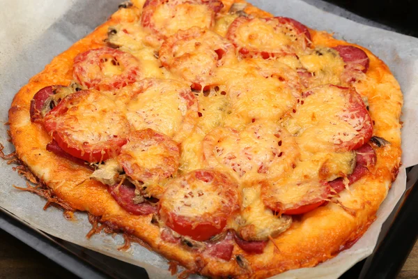 Homemade pizza on baking paper close up — Stock Photo, Image