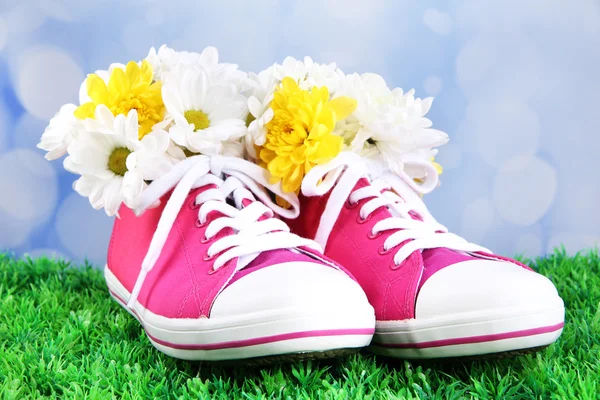 Beautiful gumshoes with flowers inside on green grass, on bright background — Stock Photo, Image