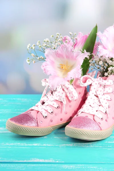 Hermosos zapatos de goma con flores en el interior en la mesa de madera, sobre fondo brillante —  Fotos de Stock