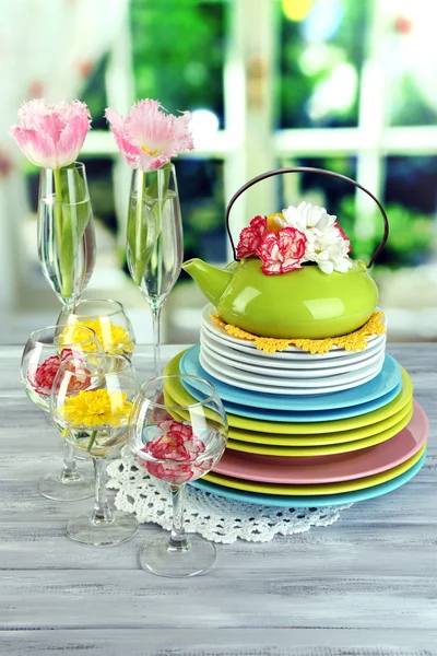 Lot de plats et fleurs en céramique colorée, sur table en bois, sur fond clair — Photo