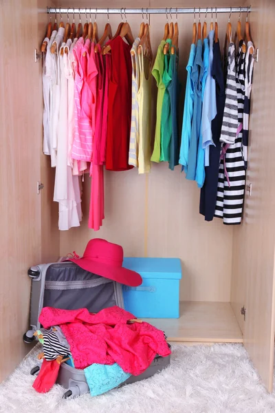 Female clothes in wardrobe and suitcase in room — Stock Photo, Image