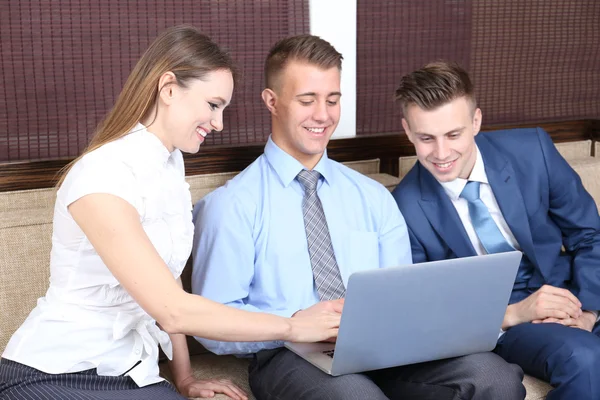 Young business people sitting on couch in office — Stock Photo, Image