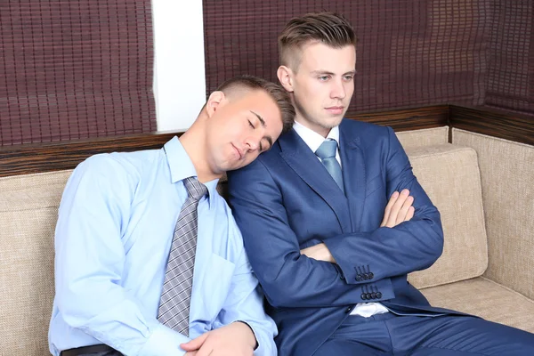 Young business people sitting on couch in office — Stock Photo, Image