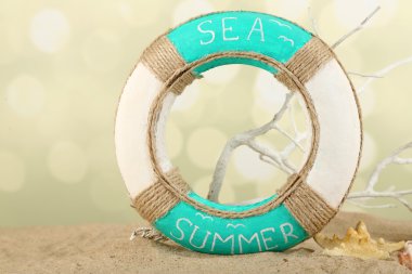 Lifebuoy ve deniz kabukları üzerinde açık renkli kum üzerinde