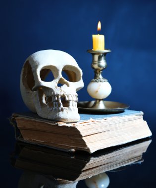kafatası ve koyu renk arka plan üzerinde eski kitap üzerine mum
