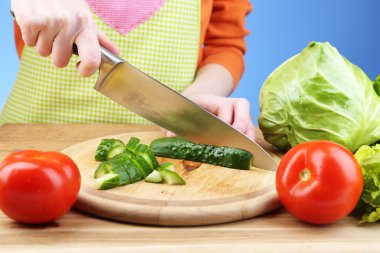 erkek eller kesim salatalık üzerinde ahşap masa, yakın çekim, mavi zemin üzerine