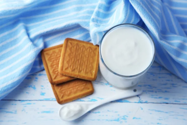 Yogurt fatto in casa in vetro e gustoso biscotto su sfondo tavolo di legno — Foto Stock