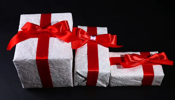 Hermosos regalos con cintas rojas, sobre fondo oscuro — Foto de Stock