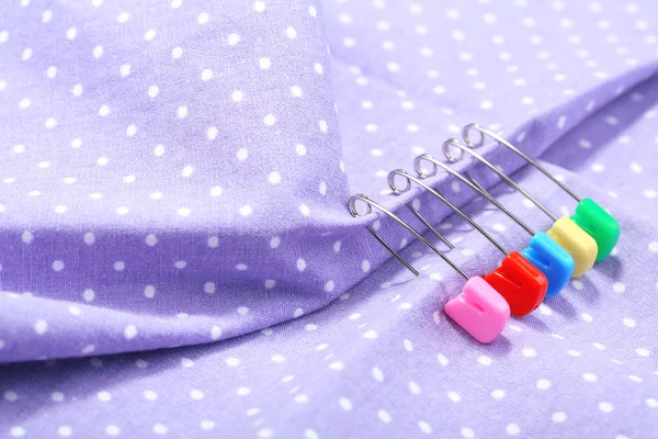 Safety pins on fabric background — Stock Photo, Image