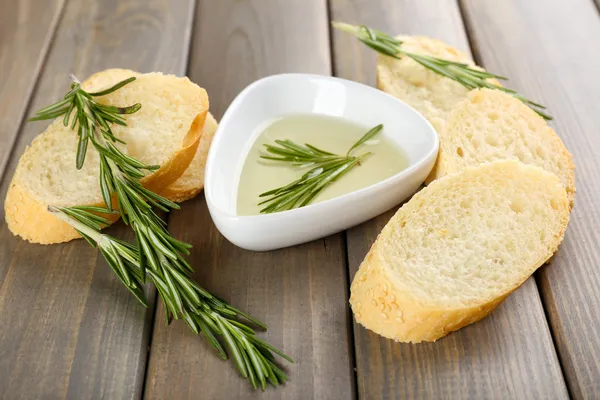 Vers brood met olijfolie en rozemarijn op houten tafel — Stockfoto