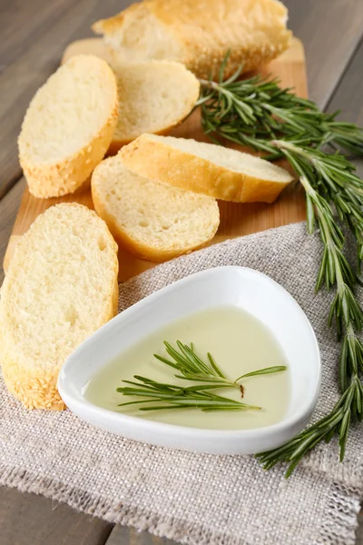 Vers brood met olijfolie en rozemarijn op houten tafel — Stockfoto