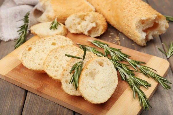 Fresh bread with olive oil and rosemary on wooden table — Stock Photo, Image