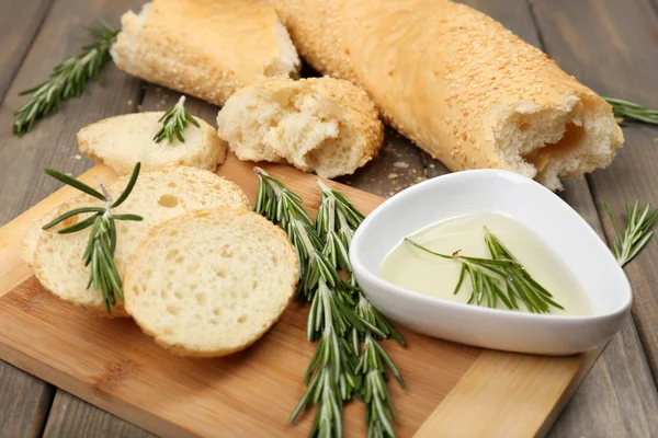 Pão fresco com azeite e alecrim sobre mesa de madeira — Fotografia de Stock