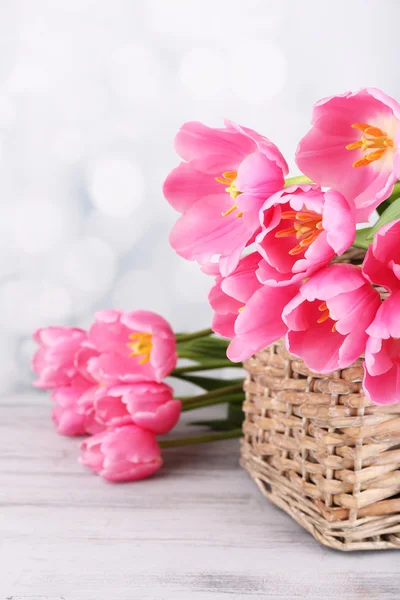 Belas tulipas cor-de-rosa na cesta na mesa de madeira — Fotografia de Stock