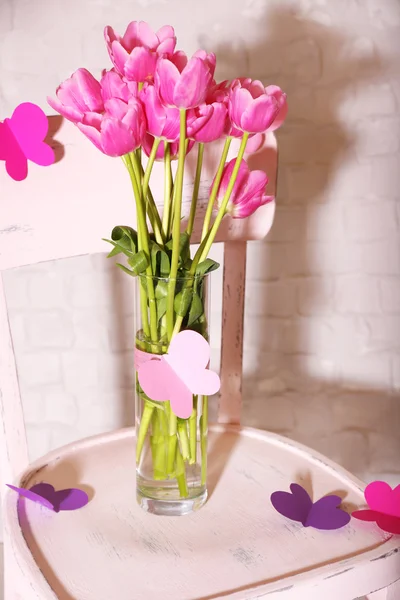 Composición con ramo de tulipanes en jarrón, en silla, sobre fondo de pared —  Fotos de Stock