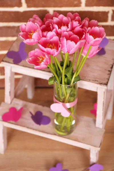 Composition with bouquet of tulips in vase, on ladder, on wall background — Stock Photo, Image