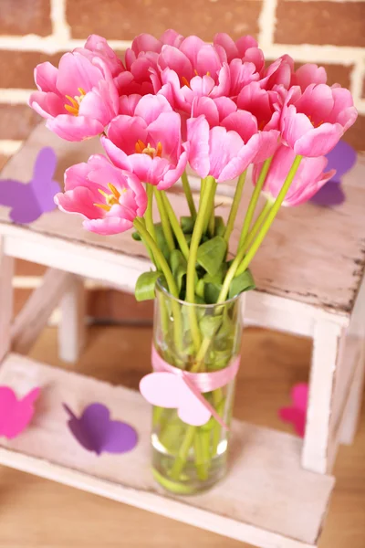 Samenstelling met boeket van tulpen in de vaas, op de ladder, op muur achtergrond — Stockfoto