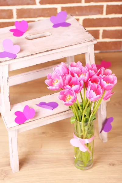Composição com buquê de tulipas em vaso, na escada, no fundo da parede — Fotografia de Stock