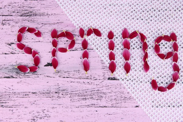 Romantický jarní dopisy vyrobené z růžových lístků, na barevné dřevěné pozadí — Stock fotografie
