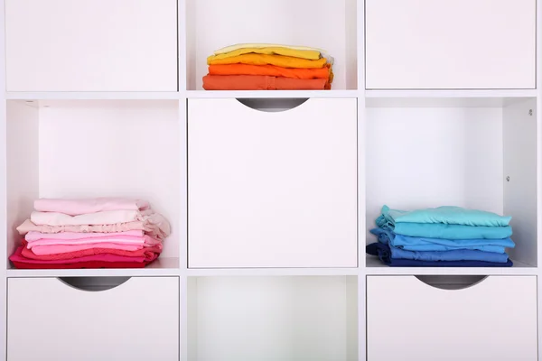 Prateleiras brancas com roupas coloridas de perto — Fotografia de Stock