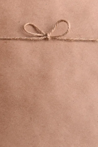 Ciąg wkomponowane w łuk na brązowy papier opakowania szczelnie-do góry — Zdjęcie stockowe