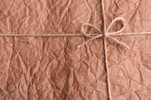 String tied in  bow on brown paper packaging close-up — Stock Photo, Image