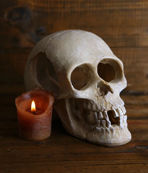 Skull and candle on wooden background — Stock Photo, Image