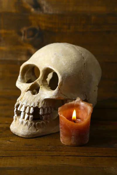 Skull and candle on wooden background — Stock Photo, Image