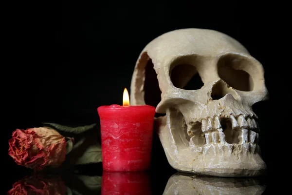 Komposition mit Totenkopf, Kerze und getrockneter Rose isoliert auf schwarz — Stockfoto