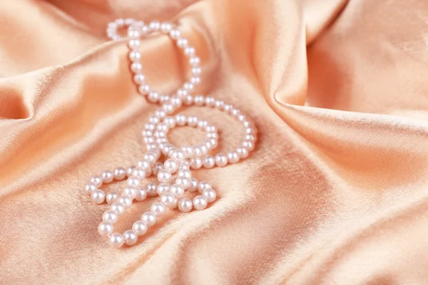 Beautiful pearls on golden silk cloth — Stock Photo, Image