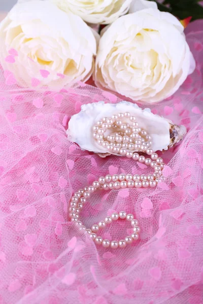 Beautiful pearls in shell on pink cloth — Stock Photo, Image